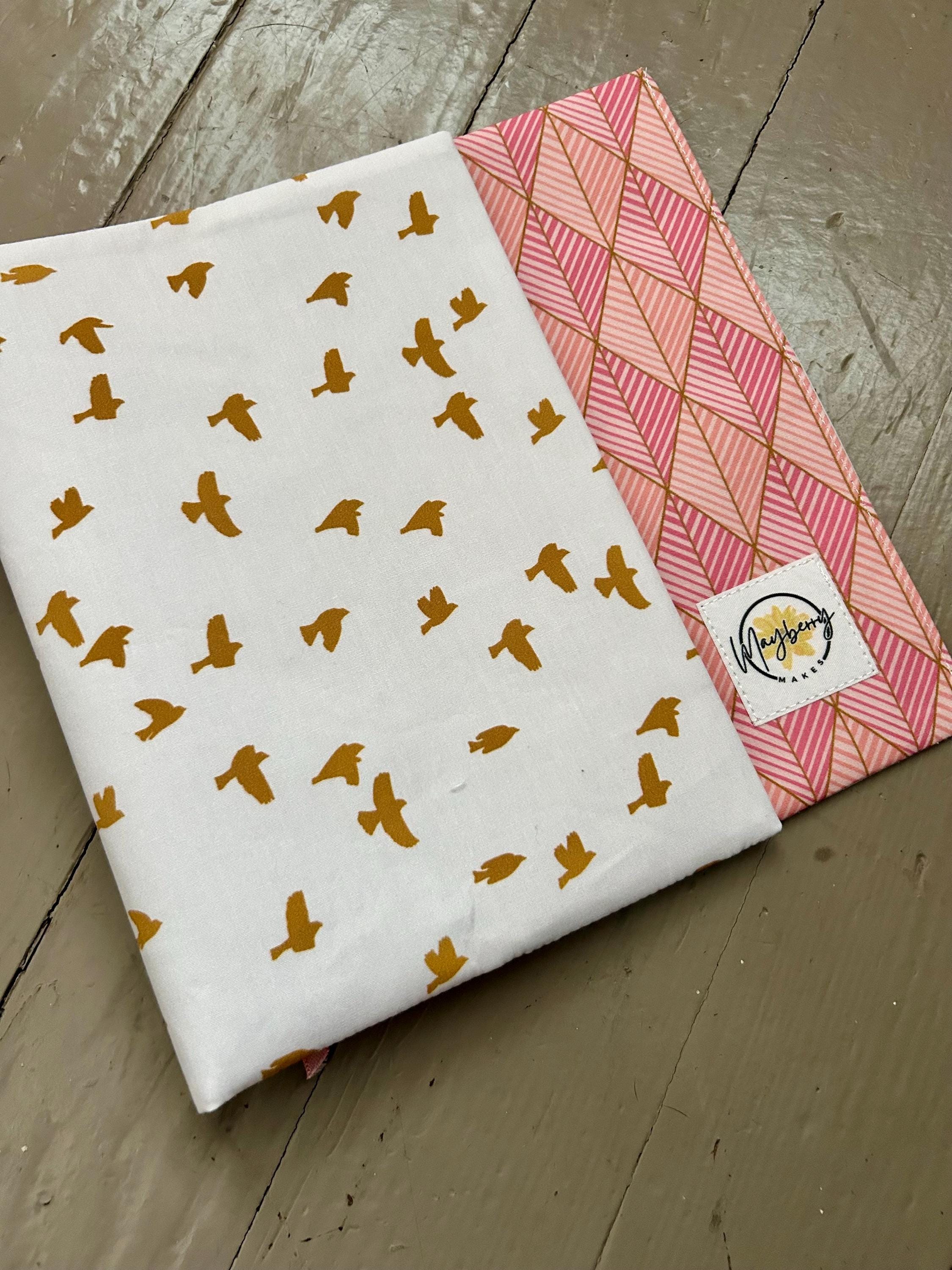 Two fabric swatches with patterns on a wooden surface