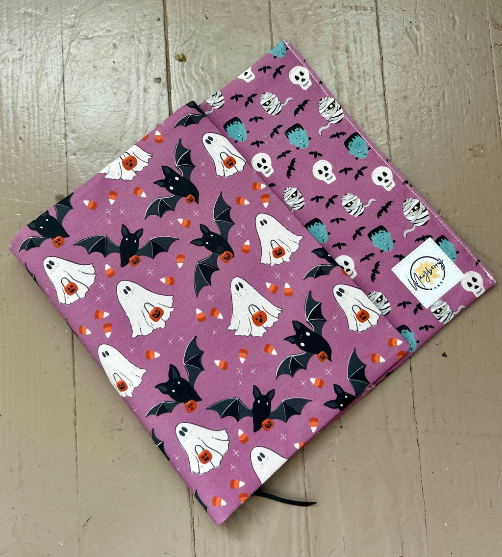 Halloween-themed notebook with ghost, bat, and candy corn pattern on a wooden surface