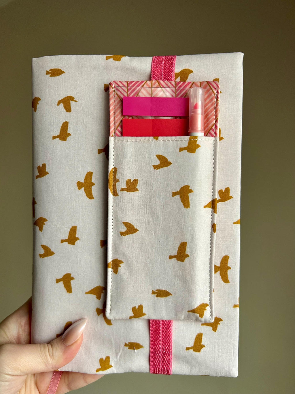 Fabric pouch with bird pattern held by a hand against a plain background